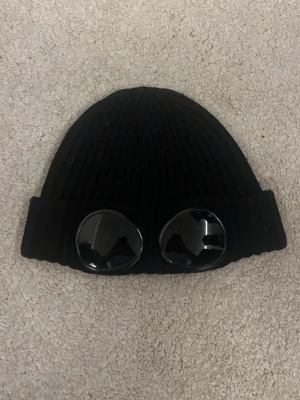 Svart C.P company mössa - Säljer min ÄKTA C.P company mösss från ASOS. Den är använd några gånger men har inte defekter eller liknande, passar lite större huvuden men inget exakt storlek men passar de flesta som e lite äldre, fint skick och inga slitage. Säljer för jag aldrig använder den. 