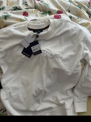 Vit Louis Vuitton sweatshirt - Vit sweatshirt från Louis Vuitton med upphöjt rutmönster och broderad logga framtill. Tröjan har rund halsringning, långa ärmar och ribbade muddar. Perfekt för en clean och lyxig streetstyle-look. Storlek L men passar M