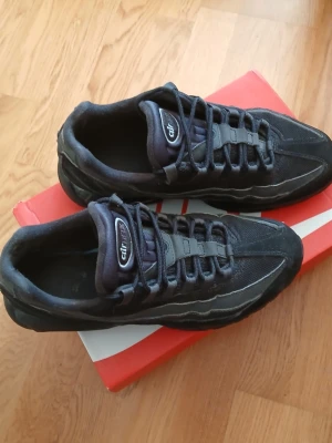 Nike Air Max 95 svarta sneakers - Säljer ett par svarta Nike Air Max 95 sneakers med ikonisk vågig design och synlig Air-dämpning i sulan. Skorna har mesh och mockadetaljer, samt reflekterande detaljer på sidan. Perfekta för dig som gillar streetwear och sportig stil.   /Pris kan förhandlas