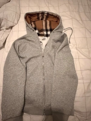Grå hoodie från Burberry med huva - Jag säljer min Burberry kofta eftersom den är för stor för mig. Jag har inte använt den nångång helt ny. Om du är intresserad eller har några frågor kontakta mig. Kan även bytas mot något!