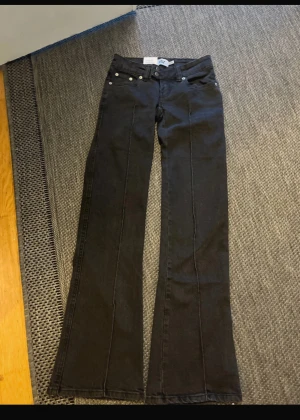Svarta jeans  - HELT NYA!!!!!! Säljer ett par svarta bootcut jeans. . Jeansen har klassisk femficksmodell, silverfärgade nitar och knapp, samt utsvängda ben. Materialet är denim med en mjuk känsla och snygg passform. Perfekta för en trendig och avslappnad stil.
