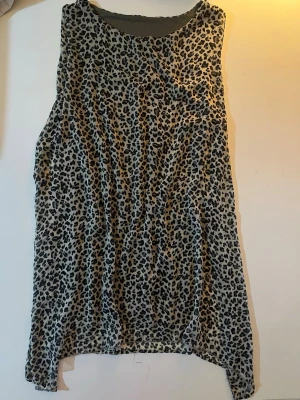 Leopardmönstrad ärmlös linnetopp - Snygg ärmlös linnetopp med leopardmönster i svart och olivgrön. Perfekt för dig som gillar thriftkläder och vill sticka ut och addera lite edge till din outfit. Tunn och luftig, passar bra till både jeans och kjol. Saknar band men går att ta på sig oavsett. Inga fläckar.