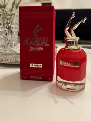 Scandal Le Parfum Jean Paul Gaultier 90ml - Scandal Le Parfum från Jean Paul Gaultier är en lyxig parfym i en röd glasflaska med en unik guldfärgad kork formad som kvinnoben. Förpackningen är också röd med guldiga detaljer och logotyp. Doften är intensiv och elegant, perfekt för dig som vill sticka ut.
