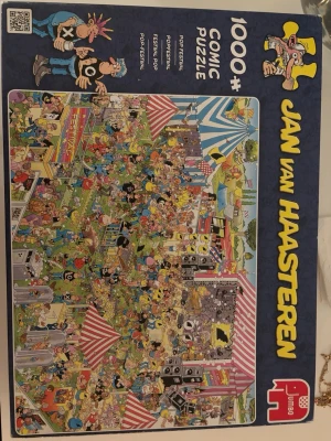 Jan van Haasteren 1000-bitar pussel - Roligt och färgglatt pussel med 1000 bitar från Jan van Haasteren. Motivet föreställer en livlig festival med massor av detaljer, tecknade figurer och tält i olika färger. Perfekt för dig som gillar utmanande och humoristiska pussel.