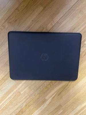 HP Laptop Intel Inside - HP laptop med Intel Inside-processor, svart chassi och fullstor tangentbord. Skärmen har några synliga fläckar, men i övrigt ser datorn ut att vara i gott skick. Perfekt för studier eller arbete. Batteriluckan och undersidan visar normalt slitage.