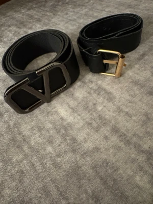 Bälte  - Säljer två svarta bälten med metallspänne. Bältet åt vänster 100cm, bältet åt höger 75cm.