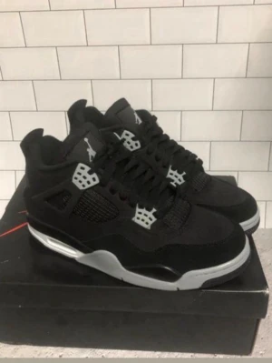 Jordan 4 - Säljer ett par svarta Nike Jordan 4 sneakers med grå och vita detaljer. Skorna har snörning, platt sula och meshpaneler på sidorna. Ikonisk Jumpman-logga på plösen och hälen. Perfekta för dig som gillar streetwear och klassisk sneakerstil. 10/12🤩