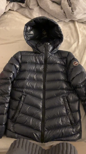 Mörkblå Colmar dunjacka med huva - Säljer min fina mörkblå jacka från Colmar som är glansig. Det står att den passar 172 cm, skulle säga att den är för någon som har storlek S/M. Säljer jackan för den kommer inte till användning. Den är super skön nu till höst/vinter. Använd max 10 gånger förra vinter så de är inga defekter. Köpt för 5500. Priset kan diskuteras. Skriv om du har någon fråga💞 