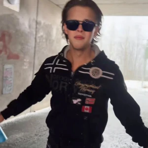 Svart hoodiejacka från Geographical Norway - Svart hoodiejacka med dragkedja från Geographical Norway. Jackan har broderade loggor och flaggor på bröstet och ärmen, samt två fickor framtill. Huva med dragsko och vita detaljer på axlar och bröst.