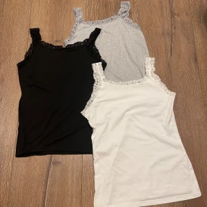 3-pack spetskantade linnetoppar (FRI FRAKT TILL 5/1)‼️ - Säljer tre linnetoppar med spetskantade axelband och halsringning. En är svart med svart spets, en vit med vit spets och en ljusgrå med grå spets. Alla är ärmlösa och har en slim passform. Perfekt att styla lager på lager eller som de är.