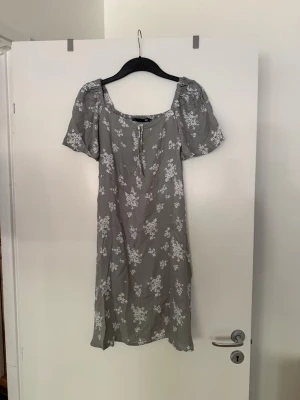 Klänning grå med vita blommor  - Storlek XS. Aldrig använd. 