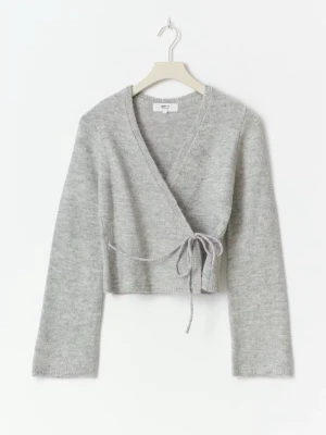 Grå omlottkofta från Gina Tricot - Säljer en ljusgrå omlottkofta från Gina Tricot med knyt i midjan. Koftan är stickad, har lång ärm och v-ringad hals. Perfekt att slänga på sig när det är lite kyligt ute. Snygg och enkel att matcha med jeans eller kjol.