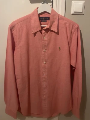 Mörk rosa  slim fit skjorta från Ralph Lauren - Säljer en snygg rosa skjorta från Ralph Lauren i slim fit-modell. Skjortan är tillverkad i bomull med stretch och har klassisk krage. Skjortan är helt oanvänd och är i ny skick.
