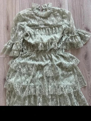 Ljusgrön spetsklänning från Bubbleroom - Superfin ljusgrön klänning från Bubbleroom i storlek 36. Klänningen har volanger, spetsdetaljer och ett blommigt mönster. Den har långärmade ärmar med extra volang och hög hals.