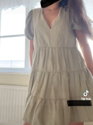 Olivgrön kortklänning  - Säljer en ljus olivgrön kortklänning med puffiga kortärmar och v-ringad hals. Klänningen har fler  flowy och luftig känsla. Perfekt för varma dagar och har en avslappnad passform.