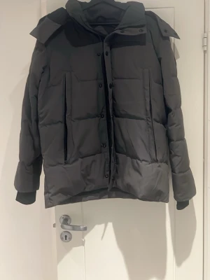  Canada Goose Wyndham (black label) - Säljer denna canada goose vinterjackan pga av att jag har vuxit ur den. Den är i ett mycket bra skick, den har en skada vilket är att dom två knapp hålen har böjts(se bild) vilket går och fixa annars har den inga andra skador. Kan inte garantera äkthet eftersom jag fick den i present i 2023, därav priset!