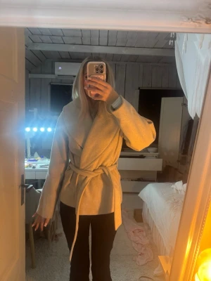 Beige omlott kappa med bälte - Jättefin ljusbeige kappa från vero moda. Den är i strlk m men passar mig som oftast bär xs/s. Den har blivit lite nopprig så om det önskas kan jag skicka bild på det. 