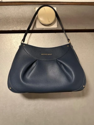  Michael Kors väska  - Snygg blå axelväska från Michael Kors i mjukt skinn med guldfärgade detaljer och stilren form. Väskan är oanvänd ❣️