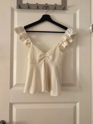 Söt topp från Gina tricot  - Fin topp från Gina tricot med volanger längs ärmarna. Nästan aldrig använd. Storlek Xs. Nypris ~200