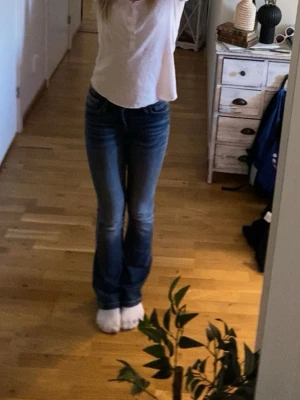 Blå bootcut jeans med låg midja - Säljer mina absoluta favorit jeans med bootcut-modell och låg midja då de tyvärr blivit försmå. Jeansen har klassisk femficksdesign, markerade sömmar och är tillverkade i stretchigt denim för en bekväm passform. Perfekta för dig som gillar en retroinspirerad look.