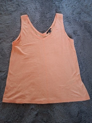 Persikofärgad linnetopp från Esmara - Säljer en persikofärgad linnetopp från Esmara i storlek S. Toppen har v-ringad hals och är ärmlös, tillverkad i mjuk bomull. Perfekt för varma dagar och enkel att matcha med jeans eller shorts.