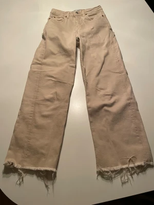 Beige wide jeans från Lager 157, XS - Snygga beige jeans från Lager 157 i storlek XS med breda ben och råa, fransiga kanter längst ner. Klassisk femficksmodell med knapp och dragkedja framtill. Perfekt för dig som gillar en chill och trendig look.