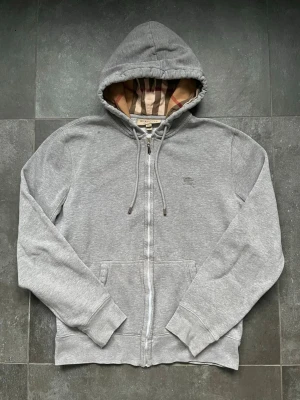 Burberry zip hoodie - Burberry zip hoodie grå i använt skick, aningen urtvättad, 2 fläckar finns och utbytt zipper, storlek M. 