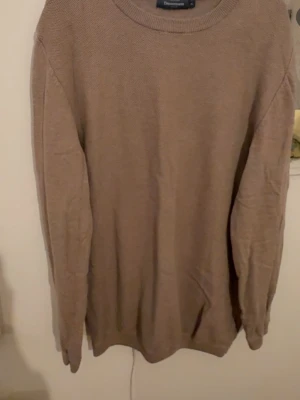Beige stickad tröja Dressmann XL - Säljer en beige stickad tröja från Dressmann i storlek XL. Tröjan har rund halsringning och långärmade ärmar. Materialet är mjukt och stickat, perfekt för kyliga dagar. Enkel och stilren design som funkar till många olika outfits.
