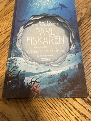 Pärlfiskaren: Legenden om ögonstenen - Följ med på ett spännande undervattensäventyr där längtan, vänskap och mod står i centrum. Boken har vunnit Runeberg Junior-priset och är nominerad till Nordiska rådets barn- och ungdomspris. Perfekt för dig som älskar magiska berättelser och episka resor!