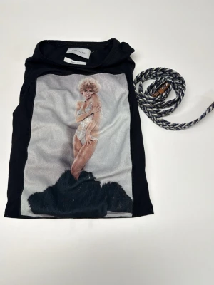 Svart t-shirt Limitato x Terry O'Neill - Svart t-shirt från Limitato med ikoniskt fotoprint framtill av Terry O'Neill. Klassisk passform och rund hals. T-shirten är i mjuk bomull och har en riktigt snygg och unik look som sticker ut. Bältet hänger med om du köper tishan! Skriv angående frågor!