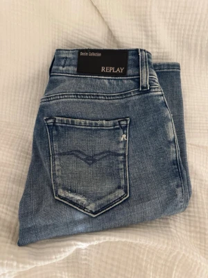 Replay bootcut jeans - Säljer ett par Replay New Luz jeans i klassisk blå tvätt med bootcut passform. Jeansen har fyra fickor, snygga slitningar och Replay-logga på fickan. Tillverkade i mjukt jeansmaterial som sitter skönt och har en tidlös look. som nya
