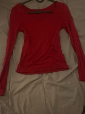 Röd långärmad topp - En enkel och snygg röd långärmad topp med rund halsringning. Modellen är figurnära och passar perfekt till jeans eller kjol. Tillverkad i mjukt material som känns skönt mot huden.