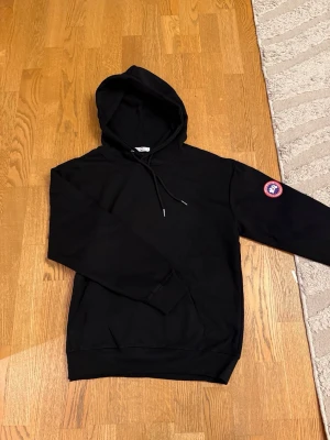 Canada goose hoodie  - En helt ny svart Canada goose hoodie. Med det vanliga Canada goose märket på armen samt en gosig luva. Kengur ficka på magen. 