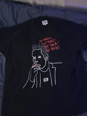 ODZ merch T-shrit - Svart t-shirt från ODZ med stor grafisk print framtill. Motivet föreställer Torsten flink och texten 'DE BRA!' i rött. ODZ-logga på bröstet. Klassisk passform och rund hals. Perfekt för dig som gillar streetwear och unika prints men framför allt ODZ. Säljer då den är för stor och benim införskaffat nya tröjor från dom