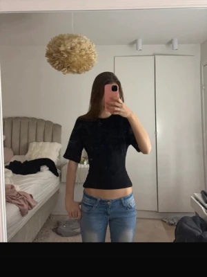 Svart croppad topp med öppen rygg - Säljer en svart croppad topp med korta ärmar och öppen rygg som knyts baktill. Toppen har en tight passform och är perfekt för dig som vill ha en trendig och stilren look. Materialet känns mjukt och följsamt mot kroppen.