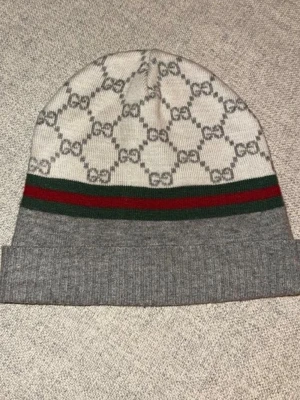 Grå och vit Gucci mössa i ull/kashmir ORIGINAL  - Säljer en snygg Gucci mössa i grått och vitt med klassiska GG-mönster och gröna samt röda ränder. Mössan är ribbstickad nedtill och tillverkad i en lyxig mix av ull och kashmir. 