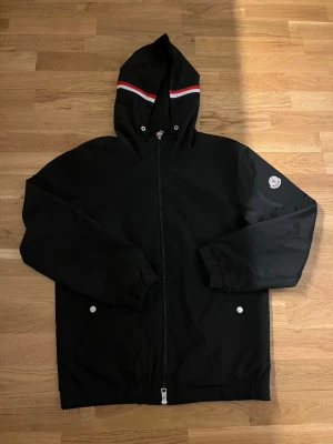 Moncler windbreaker - Säljer min vindjacka från moncler, skick 7/10 någon liten fläck annars inget fel på den. Tagit bort snörena då de var för långa. Jackan är i strl L men passar S/M. Kom privat vid mer frågor eller funderingar!