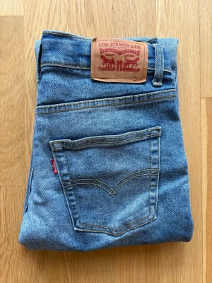 Levi's ljusblå jeans straight fit - Klassiska Levi's jeans i ljusblå tvätt med raka ben och femficksmodell. Jeansen har normal passform och är tillverkade i slitstarkt bomullsdenim. Ikonisk läderpatch bak i midjan och röda Levi's-taggen på bakfickan.