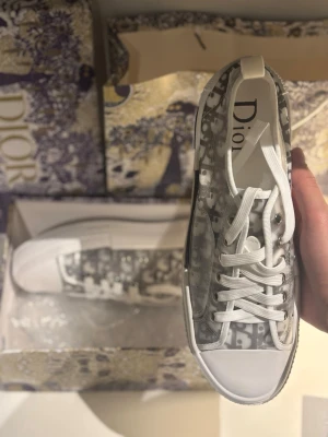 Dior B23 - Säljer dessa helt nya endast testade dior b23. Säljer pg att dem är lite små och har ej möjlighet till retur. Size 44! Dustbag, låda samt visitkort osv medkommer! Uppskattar om man inte skixkar prisförslag bara för att utan endast vid intresse.