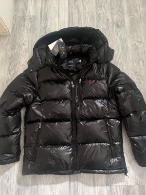 Ralph lauren jacka - Hej! En glossy Ralph lauren jacka till salu. Jackan är i jättebra skick och den har inga defekter elller tecken av användning. Jackan är köpt på Nk och kvittot finns kvar. Jag säljer jackan pågrund av att den tyvärr inte passar mig, priset kan diskuteras lite vid snabbaffär. hör av dig vid frågor 😁