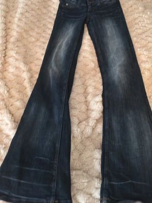 Mörkblå bootcut jeans från Cheap Monday - Säljer ett par mörkblå bootcut jeans från Cheap Monday med snygg slitning och klassisk femficksmodell. Jeansen har en bredare utsvängning nedtill och ett coolt Cheap Monday-märke bak i midjan. Perfekta för dig som gillar retrovibbar och vill sticka ut.