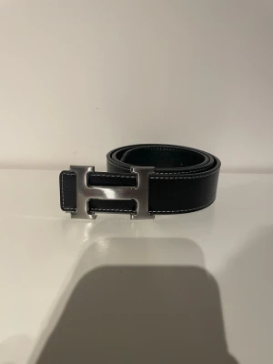 Svart H-bälte - Nytt - Säljer ett helt nytt svart designer bälte. Bältet är 105 cm långt och har aldrig använts. 