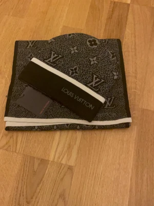 Här har vi ett svart lv sett - Snygg svart sett  från Lv  med ikoniskt monogrammönster i grått. Settethar vita detaljer längs kanterna och är tillverkad i ett mjukt stickat material. Perfekt för dig som vill ha en exklusiv och trendig look.