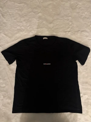 Saint Laurent Tshirt  - Skick: mycket bra, inga fläckar / hål Detaljer: 	•	Färg: svart 	•	Material: bomull 	•	Passform: regular fit 	•	storlek: M (Passar medium)  Plagget kommer från rök- och djurfritt hem.  📦 Frakt: skickas samma dag om köp går igenom innan 18.00 💬 Frågor: Hör av dig om du vill ha fler bilder eller mått 🤝 Paketpris: Samfraktar gärna vid flera köp