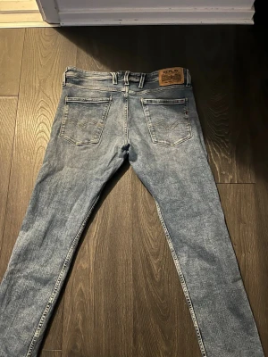 Replay Anbass  - Säljer ett par Replay Anbass i ljusblå tvätt. Klassisk femficksmodell med snygga detaljer och Replay-lapp bak i midjan. Jeansen har smal passform och är tillverkade i mjukt denimtyg för en bekväm känsla. Hör gärna av dig vid funderingar