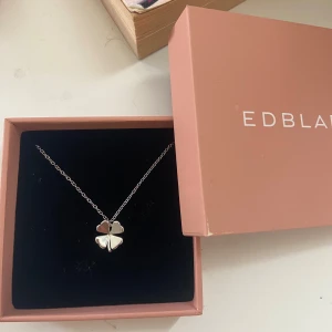 Silverhalsband med fyrklöver från Edblad - Stilrent halsband i silver från Edblad med ett hänge format som en fyrklöver. Kedjan är tunn och elegant, perfekt för att ge en subtil touch till din look. Kommer i original ask.