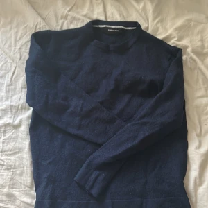 Mörkblå tröja från Lindbergh - Snygg mörkblå tröja från Lindbergh i mjuk ull. Klassisk rak modell med rund halsringning och långa ärmar. Perfekt att styla med jeans eller chinos för en clean look. Sitter som en S-XS