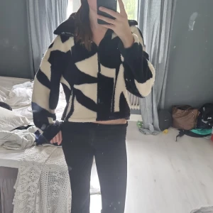 Svartvit teddyjacka från Monki XXS - Säljer en teddyjacka från Monki i storlek XXS med coolt svartvitt grafiskt mönster. Originalpris 450 kr. Jackan har dragkedja framtill, stor krage och är tillverkad i mjuk, återvunnen polyester. Perfekt för dig som gillar statement-plagg och vill ha något som sticker ut.
