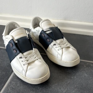 Valentino Garavani vita sneakers - Vita skor  från Valentino Garavani med bred marinblå detalj över vristen och klassisk snörning. 