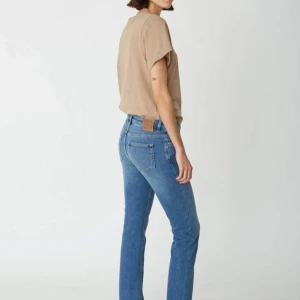 Blå raka jeans från Totême - Snygga blå jeans från Totême med raka ben och klassisk femficksmodell. Jeansen har hög midja och är tillverkade i en mix av bomull, polyester och lyocell. Fint mellanblå ”vintage”  tvätt med lätt slitning och bruna sömmar. Perfekta för en clean och stilren look.